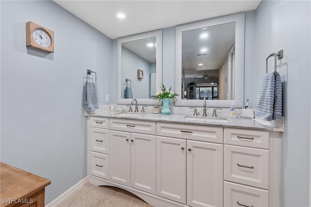 full bathroom featuring a sink, baseboards, and double vanity