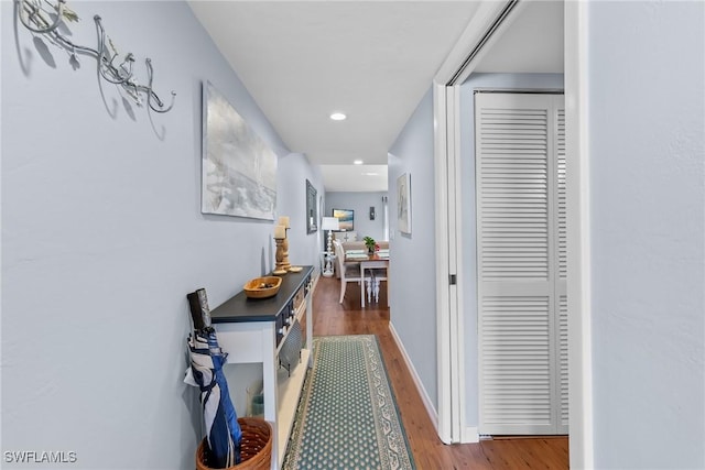 corridor with baseboards, wood finished floors, and recessed lighting