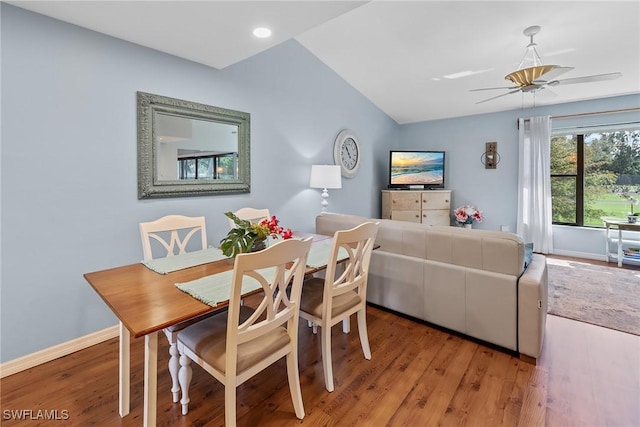 dining space featuring a ceiling fan, light wood-type flooring, vaulted ceiling, and baseboards