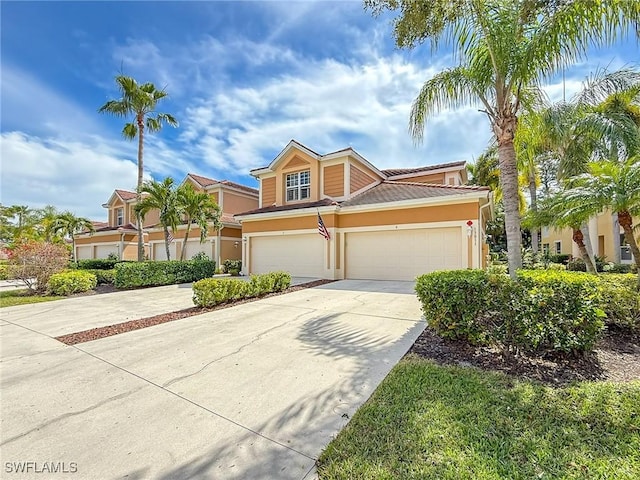 multi unit property with a garage, driveway, and stucco siding