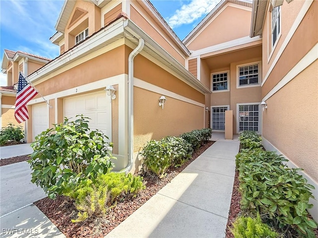 property entrance featuring a garage and stucco siding