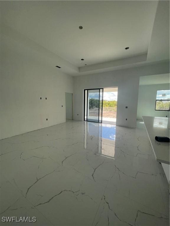 unfurnished room with marble finish floor and a tray ceiling