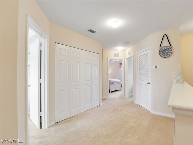 corridor with carpet, visible vents, and baseboards