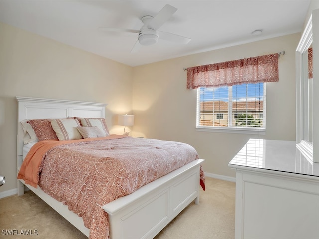 bedroom with light carpet, ceiling fan, and baseboards