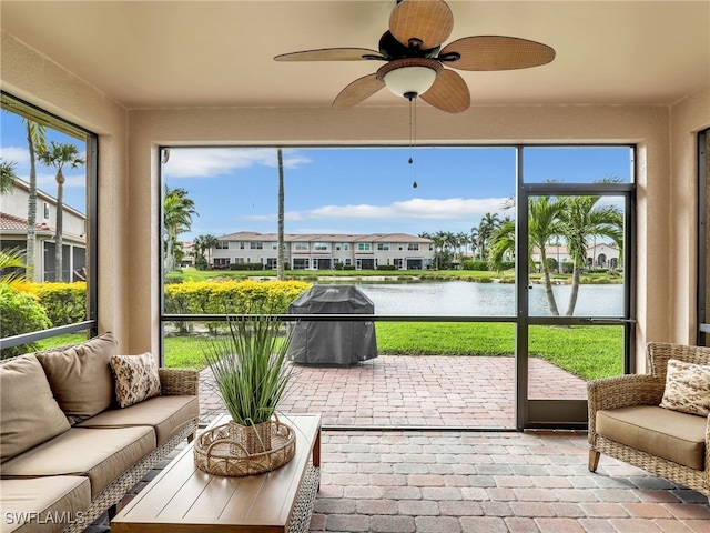 sunroom / solarium with a water view, a residential view, a wealth of natural light, and a ceiling fan