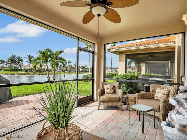 sunroom featuring a water view and ceiling fan