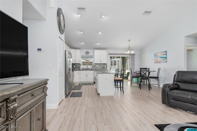 kitchen with hanging light fixtures, visible vents, white cabinets, and freestanding refrigerator