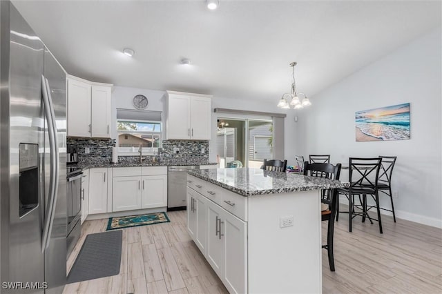 kitchen featuring a center island, pendant lighting, a breakfast bar, appliances with stainless steel finishes, and white cabinets