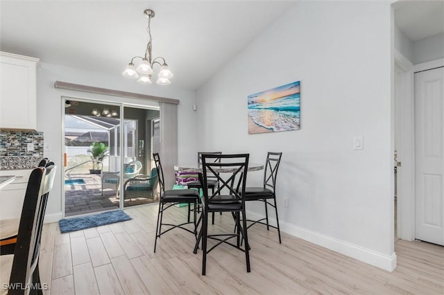 dining area with lofted ceiling, light wood finished floors, baseboards, and a notable chandelier