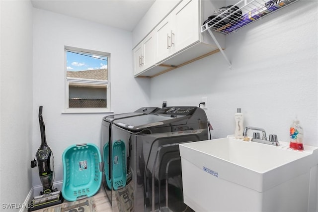 laundry room featuring independent washer and dryer, cabinet space, a sink, and baseboards