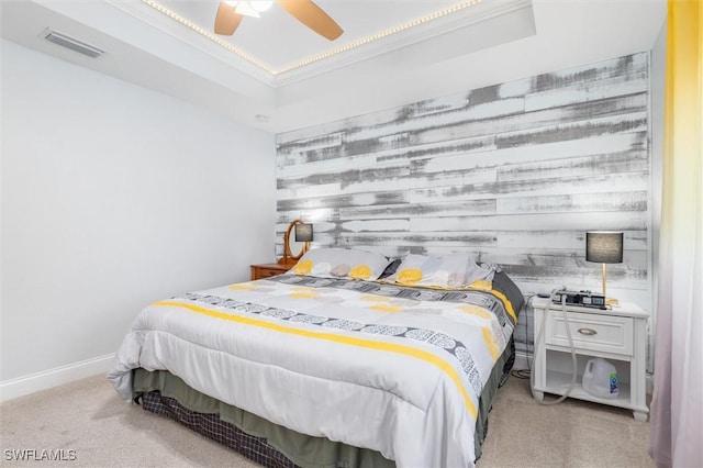 bedroom with a raised ceiling, light colored carpet, visible vents, an accent wall, and baseboards