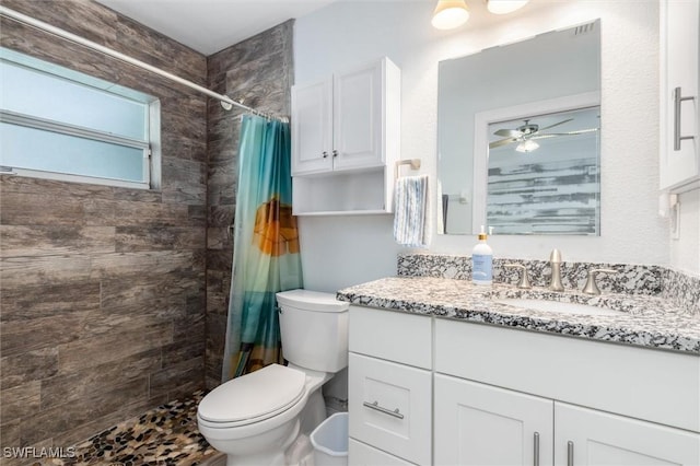 bathroom with tiled shower, ceiling fan, vanity, and toilet