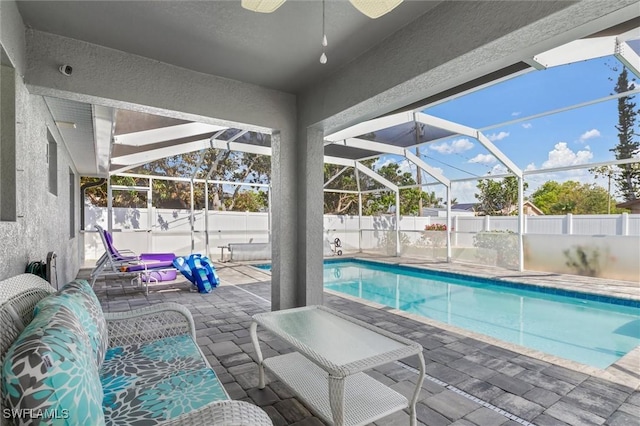 view of swimming pool with a ceiling fan, a lanai, a fenced backyard, and a patio