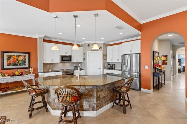 kitchen featuring arched walkways, a breakfast bar, visible vents, white cabinetry, and appliances with stainless steel finishes