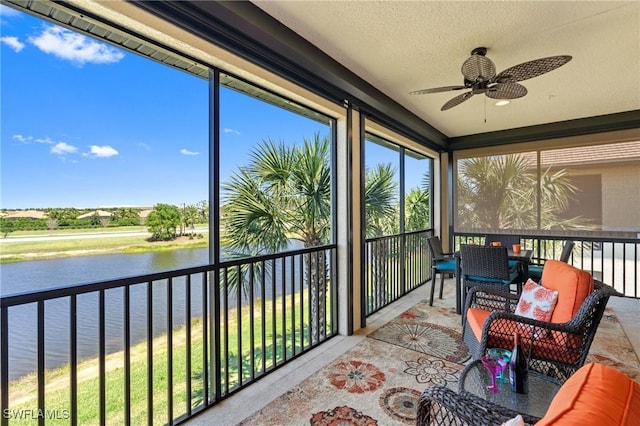 sunroom / solarium with a water view and a ceiling fan