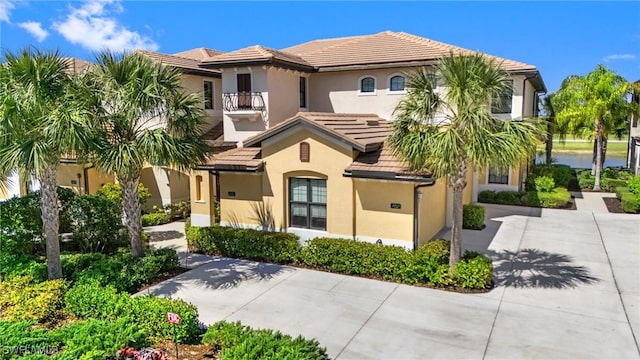 mediterranean / spanish house featuring driveway, a tile roof, a balcony, and stucco siding