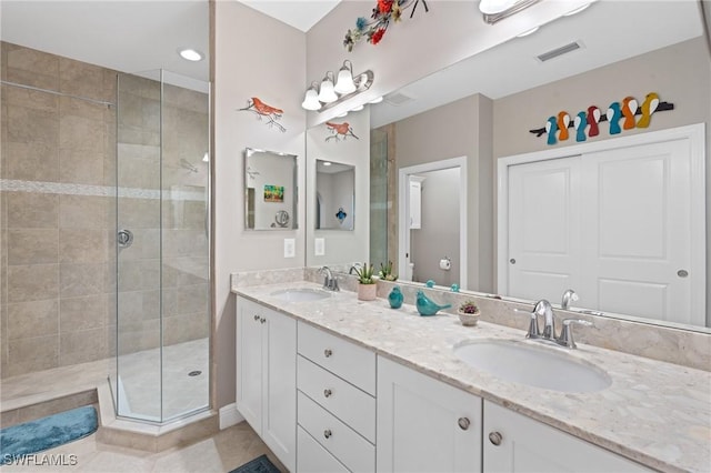 bathroom with visible vents, a sink, a shower stall, and double vanity