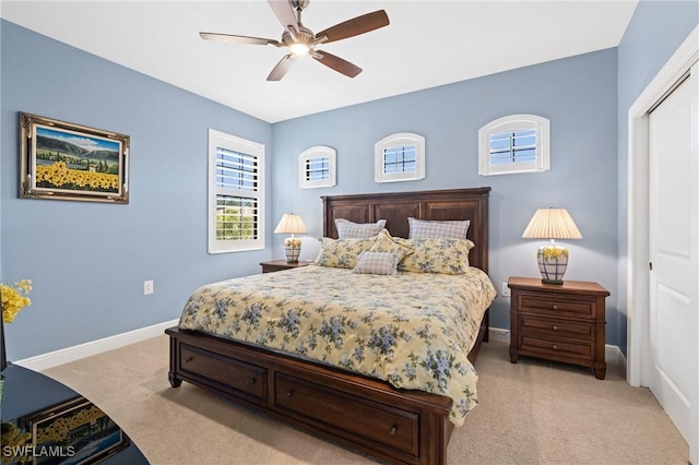 bedroom with a closet, light carpet, ceiling fan, and baseboards