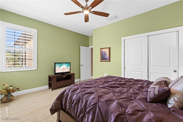 carpeted bedroom featuring ceiling fan, a closet, visible vents, and baseboards