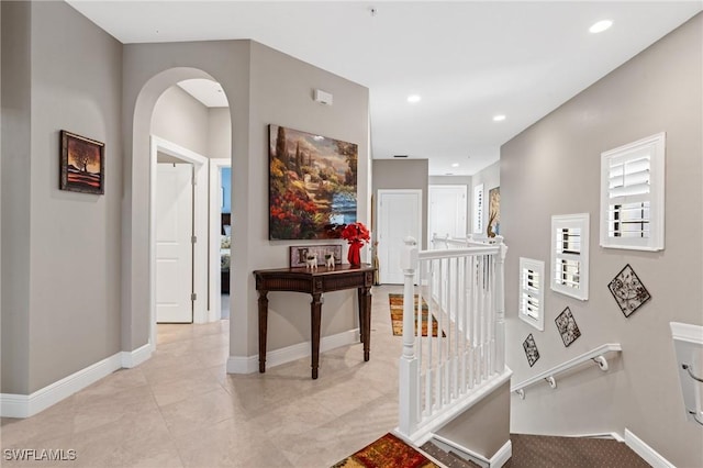 corridor featuring recessed lighting, baseboards, arched walkways, and an upstairs landing