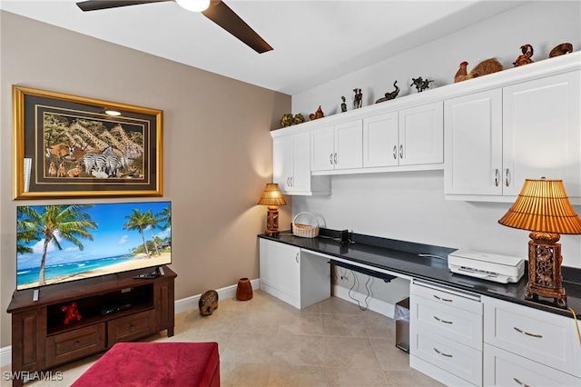 office with light tile patterned floors, ceiling fan, built in desk, and baseboards