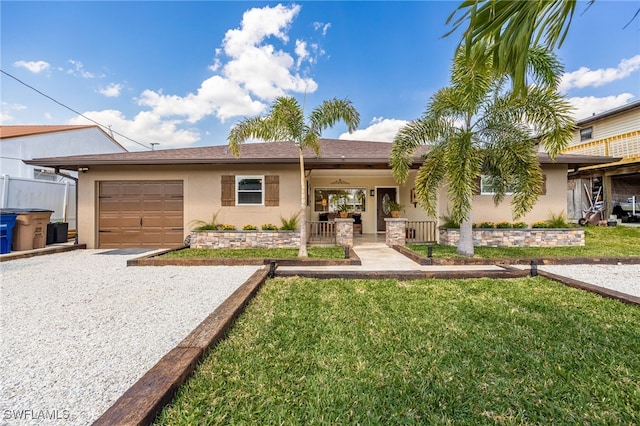 single story home featuring a garage, driveway, a front yard, and stucco siding