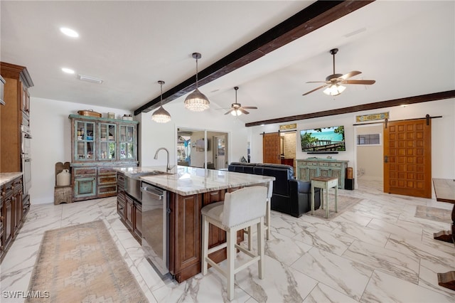 kitchen featuring a barn door, light stone counters, marble finish floor, stainless steel appliances, and a sink