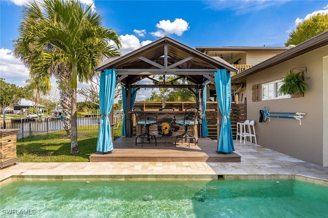 view of patio with fence, a deck, a fenced in pool, and a gazebo