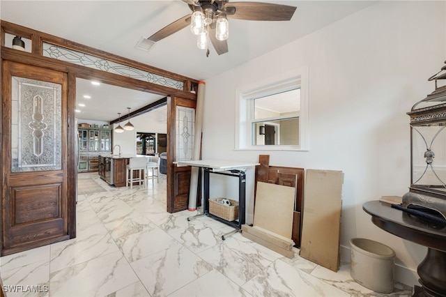 kitchen with visible vents, a kitchen breakfast bar, a ceiling fan, marble finish floor, and light countertops