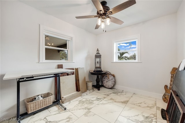 interior space featuring ceiling fan, marble finish floor, and baseboards