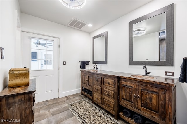 bathroom featuring double vanity, a sink, visible vents, and baseboards