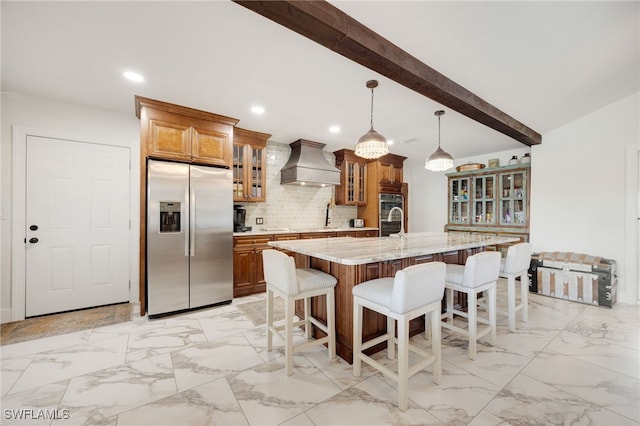 kitchen featuring a breakfast bar area, stainless steel appliances, tasteful backsplash, custom range hood, and brown cabinetry