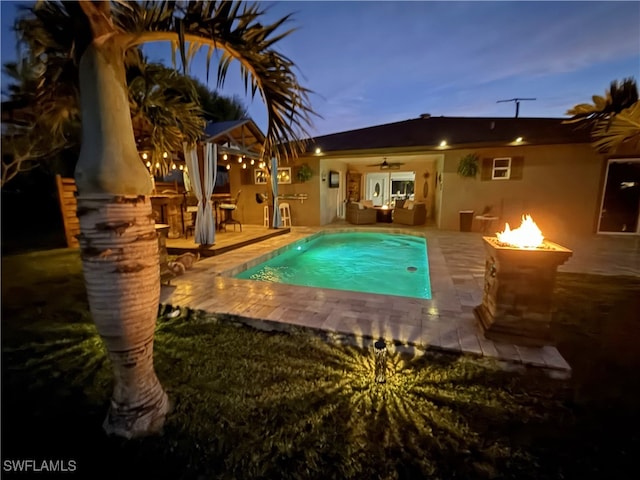 pool at dusk with a patio area and outdoor lounge area