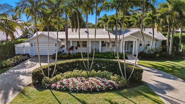 view of front facade featuring metal roof, decorative driveway, an attached garage, and a front yard