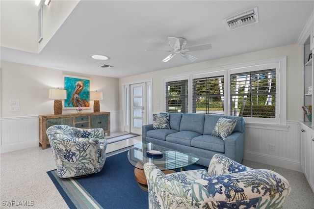 living room with a ceiling fan, wainscoting, visible vents, and speckled floor