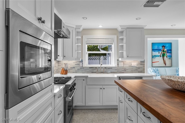 kitchen featuring light speckled floor, open shelves, visible vents, butcher block countertops, and high end stove