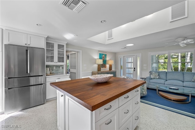 kitchen featuring butcher block counters, visible vents, light speckled floor, and high end fridge