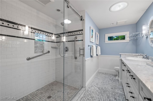 full bathroom featuring a wainscoted wall, a stall shower, vanity, and toilet