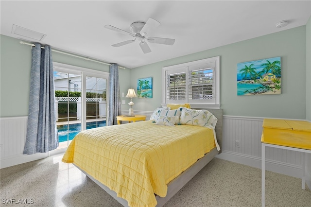 bedroom with access to exterior, wainscoting, multiple windows, and speckled floor