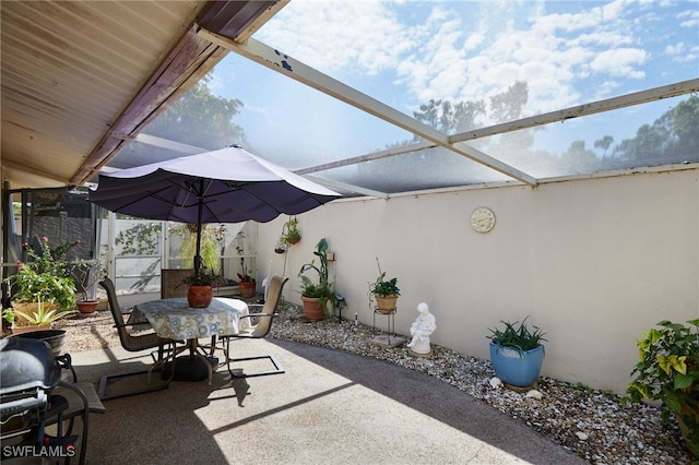 view of patio featuring outdoor dining area and glass enclosure