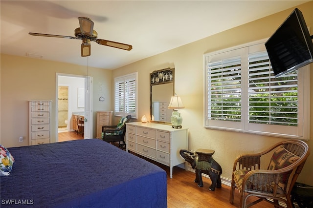 bedroom featuring light wood-style floors, visible vents, ceiling fan, and ensuite bath