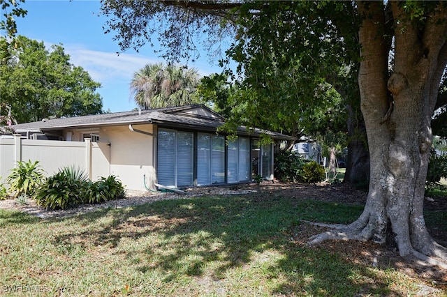 exterior space with a yard, fence, and stucco siding