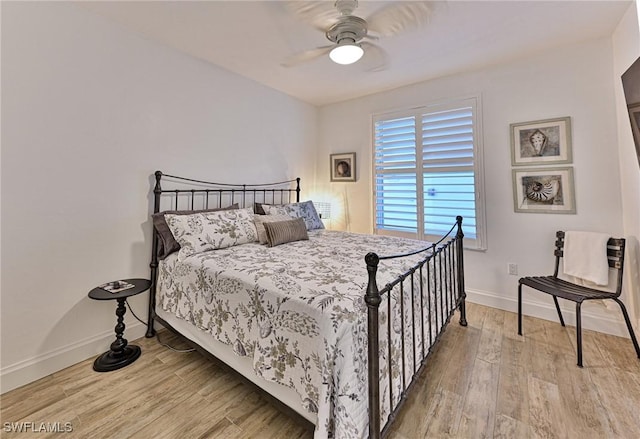 bedroom featuring baseboards, wood finished floors, and a ceiling fan