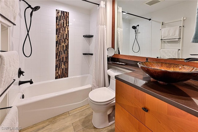 bathroom with visible vents, wood finished floors, toilet, vanity, and shower / bath combo with shower curtain