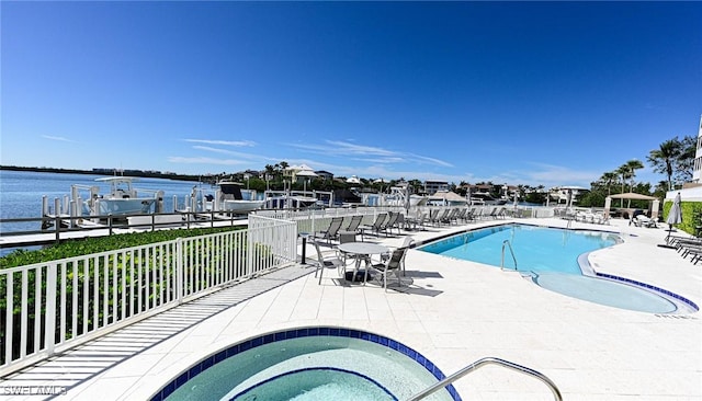 pool with a water view, a patio, and a dock