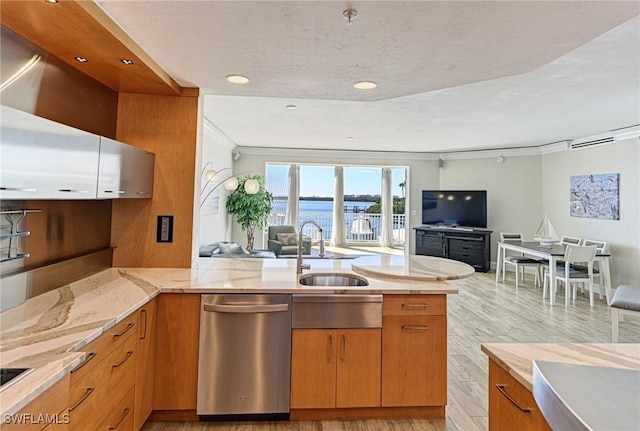 kitchen with open floor plan, crown molding, a sink, dishwasher, and light stone countertops