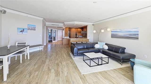 living room featuring baseboards, light wood-type flooring, and ornamental molding