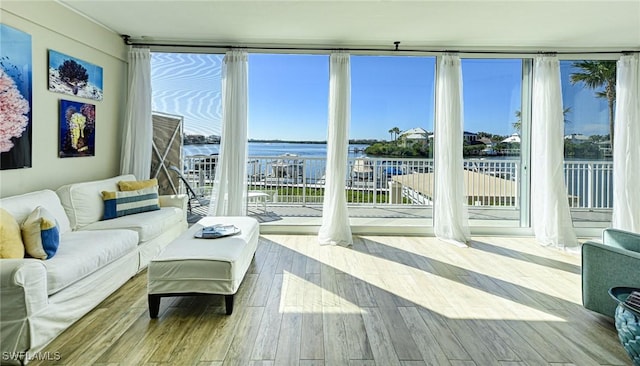 living area with expansive windows, a water view, and wood finished floors