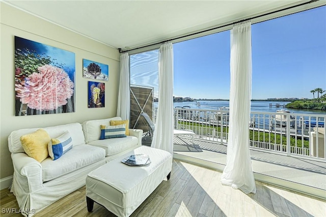 living room featuring wood finished floors, a water view, and floor to ceiling windows