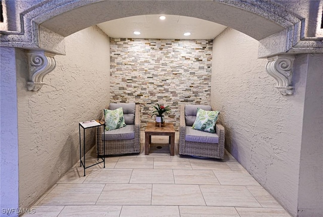 living area with a textured wall, arched walkways, and recessed lighting